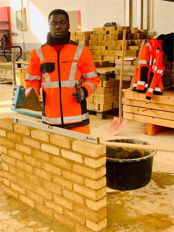 An ETALL student in site clothing in front of a brick wall during training in Germany