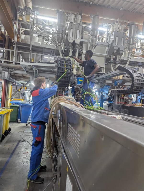 An ETALL student and a German colleague working on a machine in a workshop