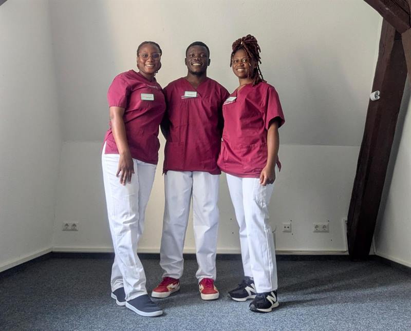 Three former ETALL students in nursing uniform at their training institution in Germany